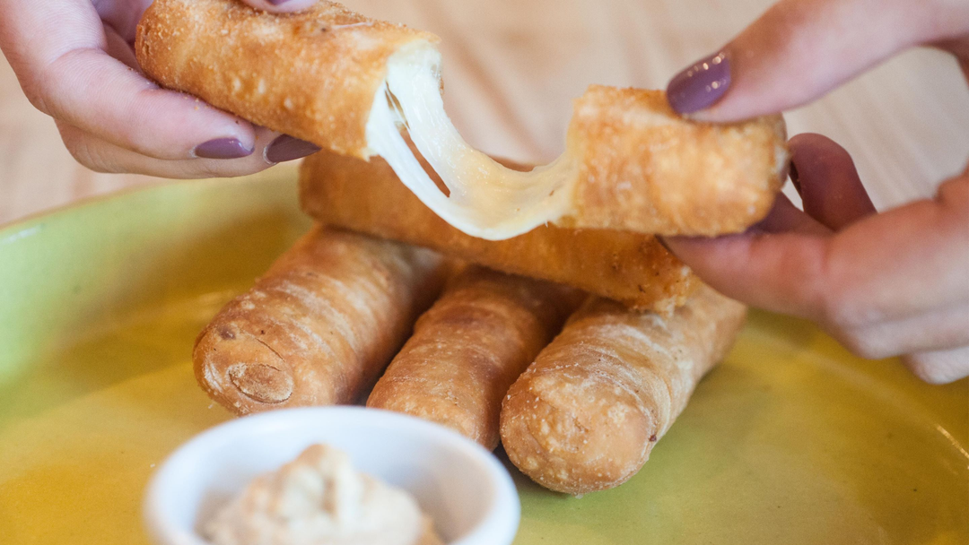 Woman holding a tequeno with melted cheese 