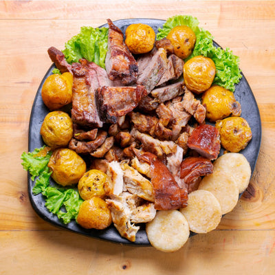 A plate with savory grilled beef, chicken, colombian potatos and four grilled Colombian arepas