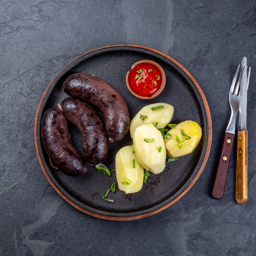 Colombian morcilla blood sausages with potatoes and chile sauce elegantly plated on a dark grey dish